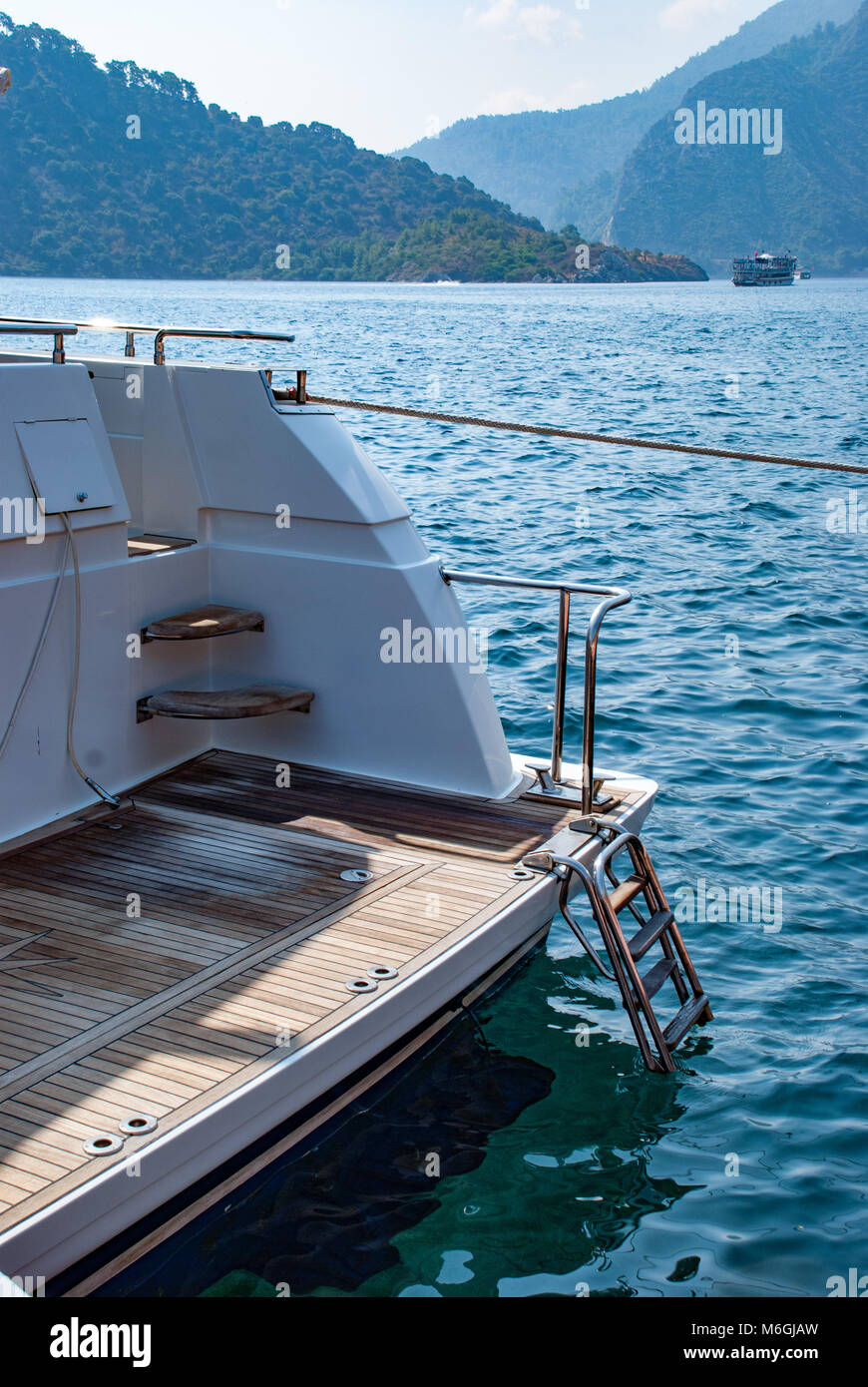 Ladder on deck of sailing yacht above rippled blue water in bright ...