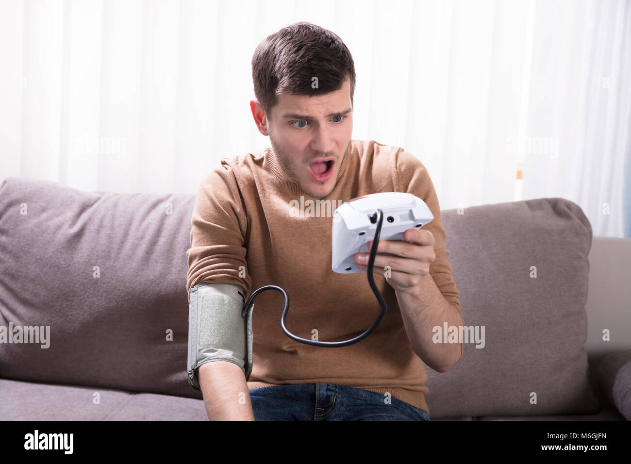 Surprised Young Man Measuring His Blood Pressure At Home Stock Photo ...