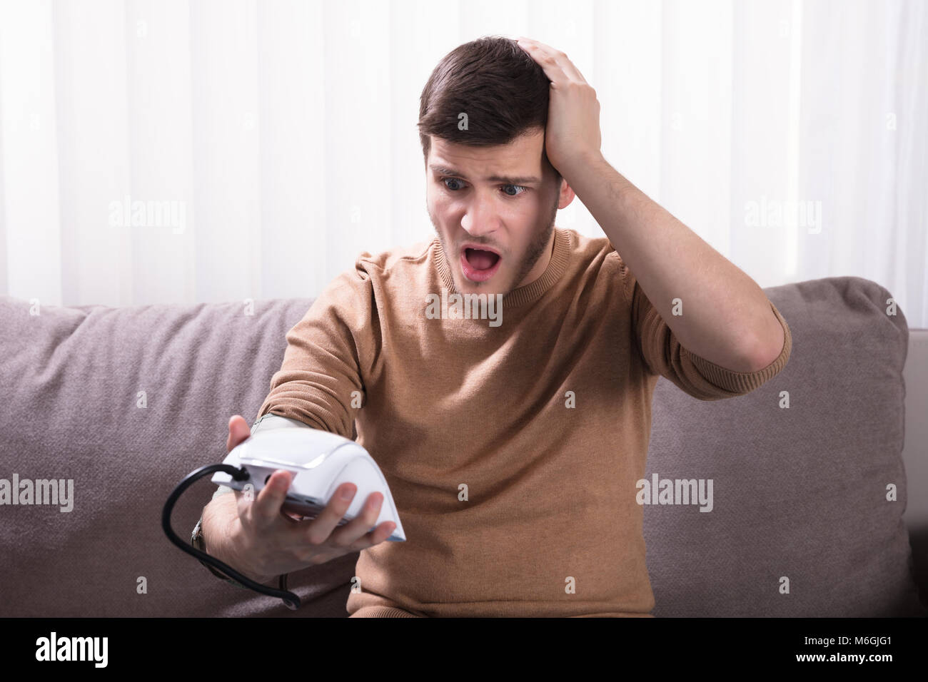 Surprised Young Man Measuring His Blood Pressure At Home Stock Photo ...