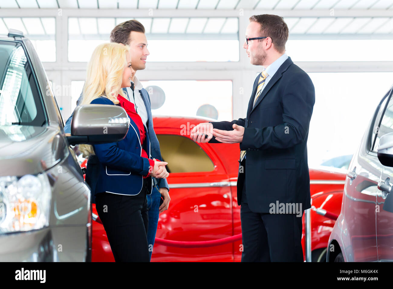 Couple buying new car at auto dealership Stock Photo