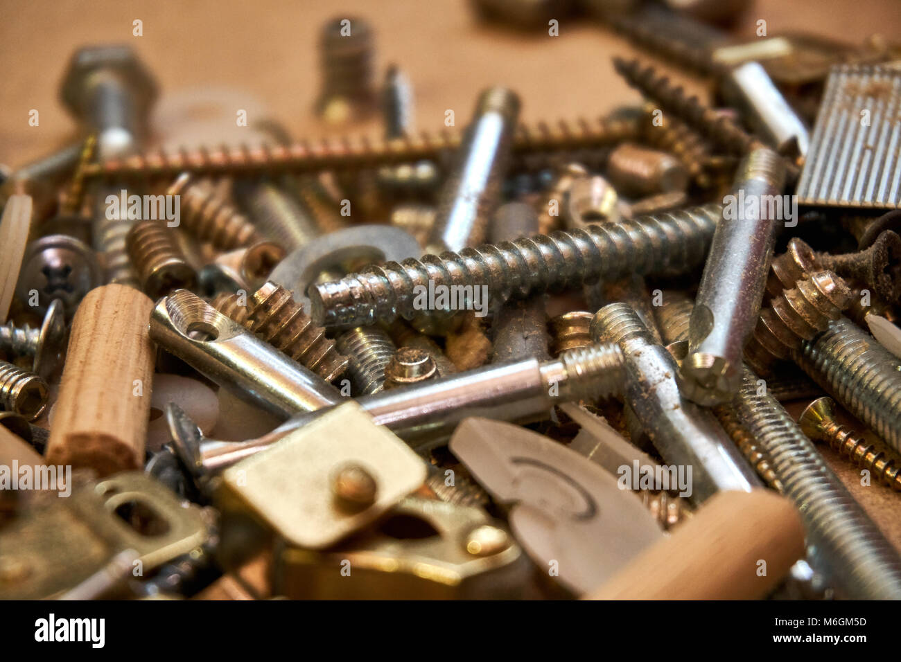 Close up view of variety of screws, nails, bolts, and other hardware products of various metals are strewn across a workstation Stock Photo