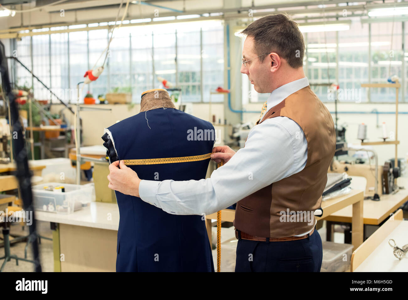 Tailor measuring jacket on mannequin in his workshop Stock Photo