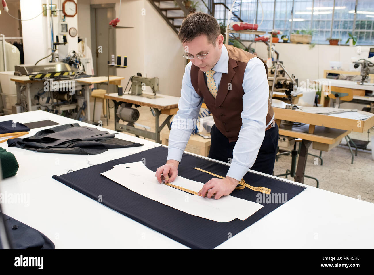 Tailor working over paper pattern of jacket in workshop Stock Photo