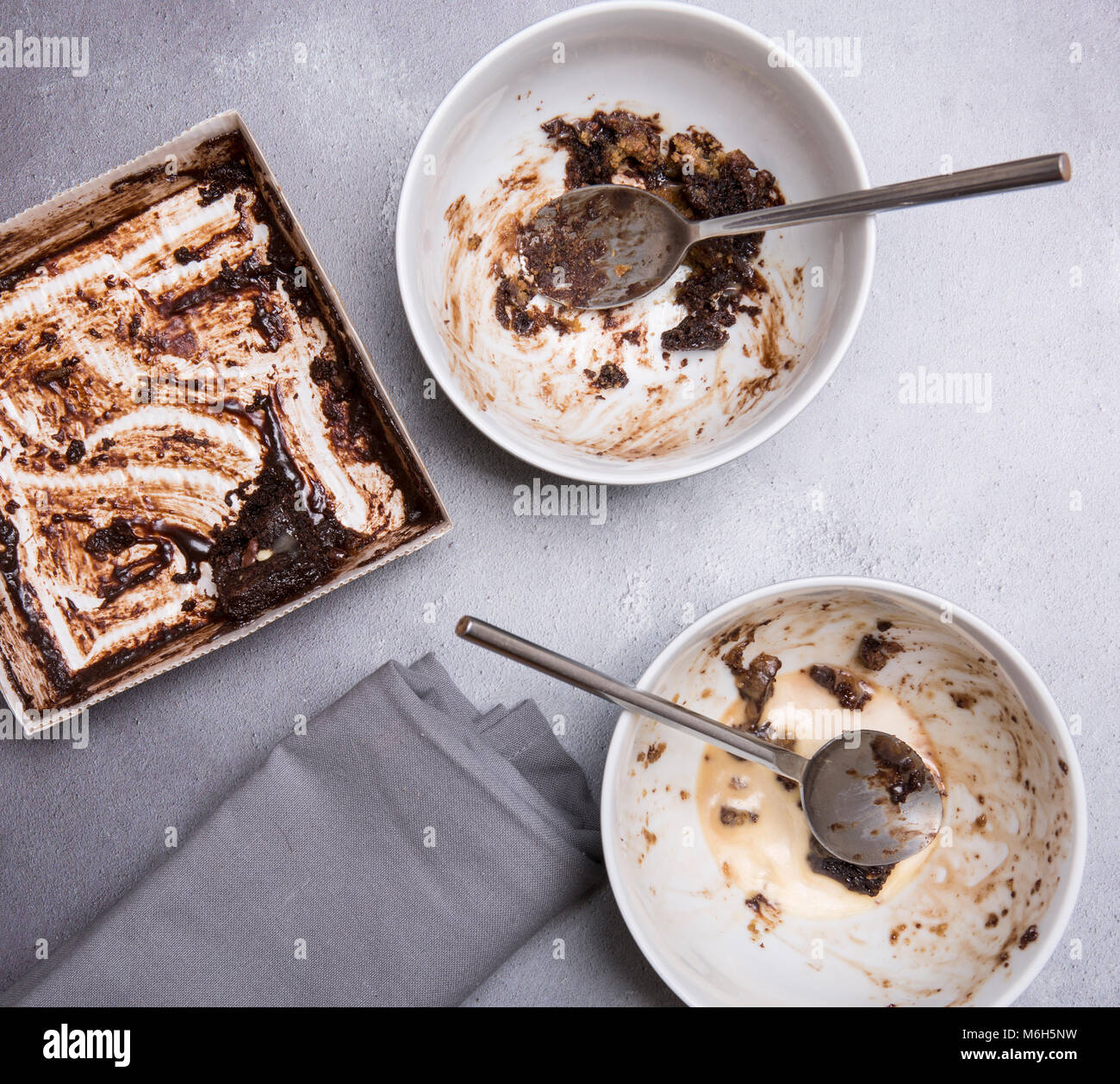 Chocolate pudding leftovers on a grey textured background with mapkin spoons and bowls Stock Photo