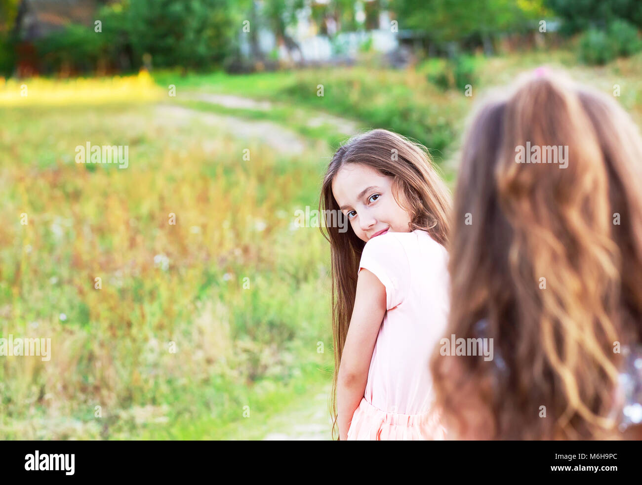 Beautiful young girl with long brunette hair, looking to camera at summer day. Having fun of joyful kid. Place for text Stock Photo
