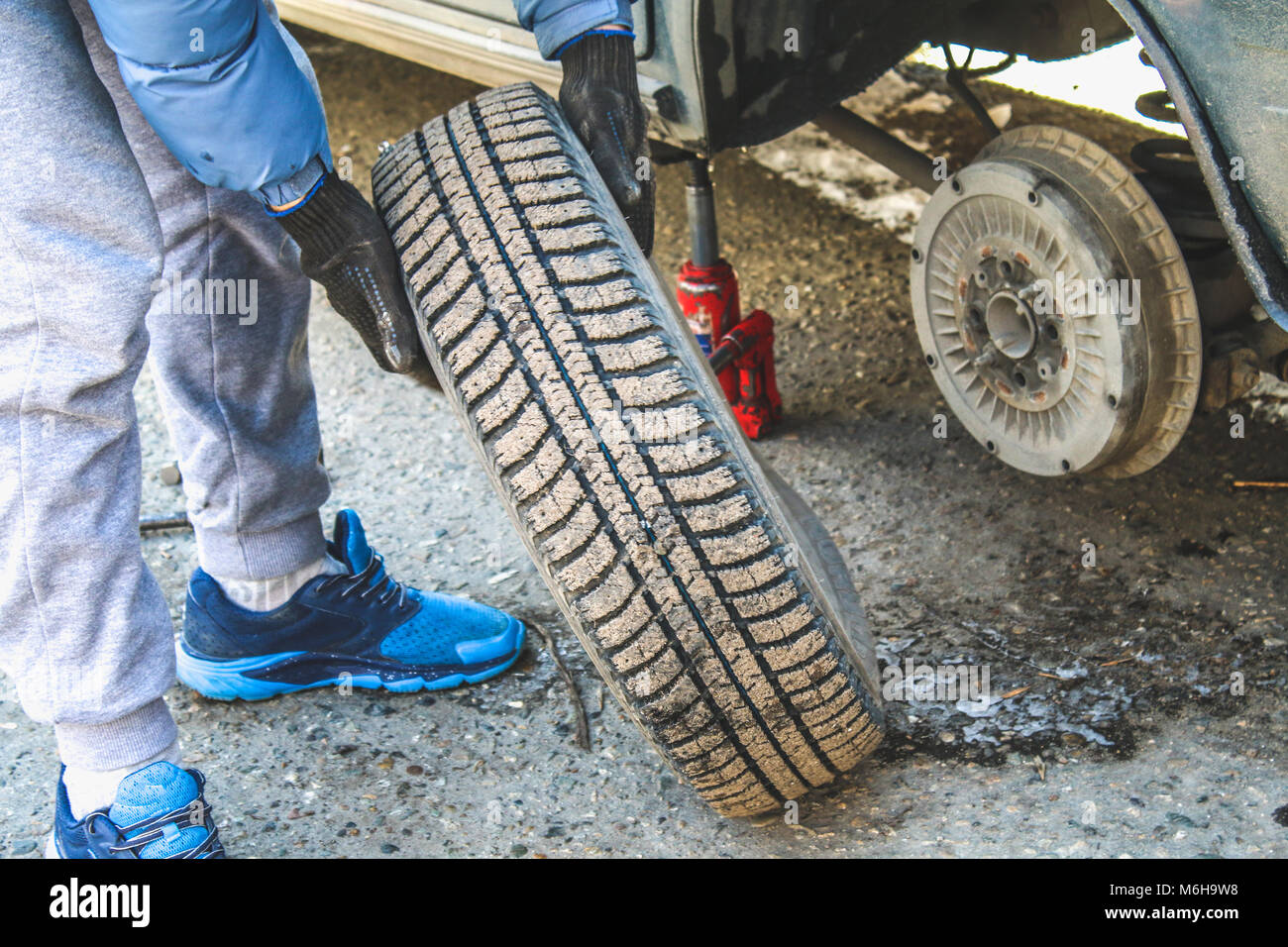 Replacing lug nuts by hand while changing tires on a vehicle Stock