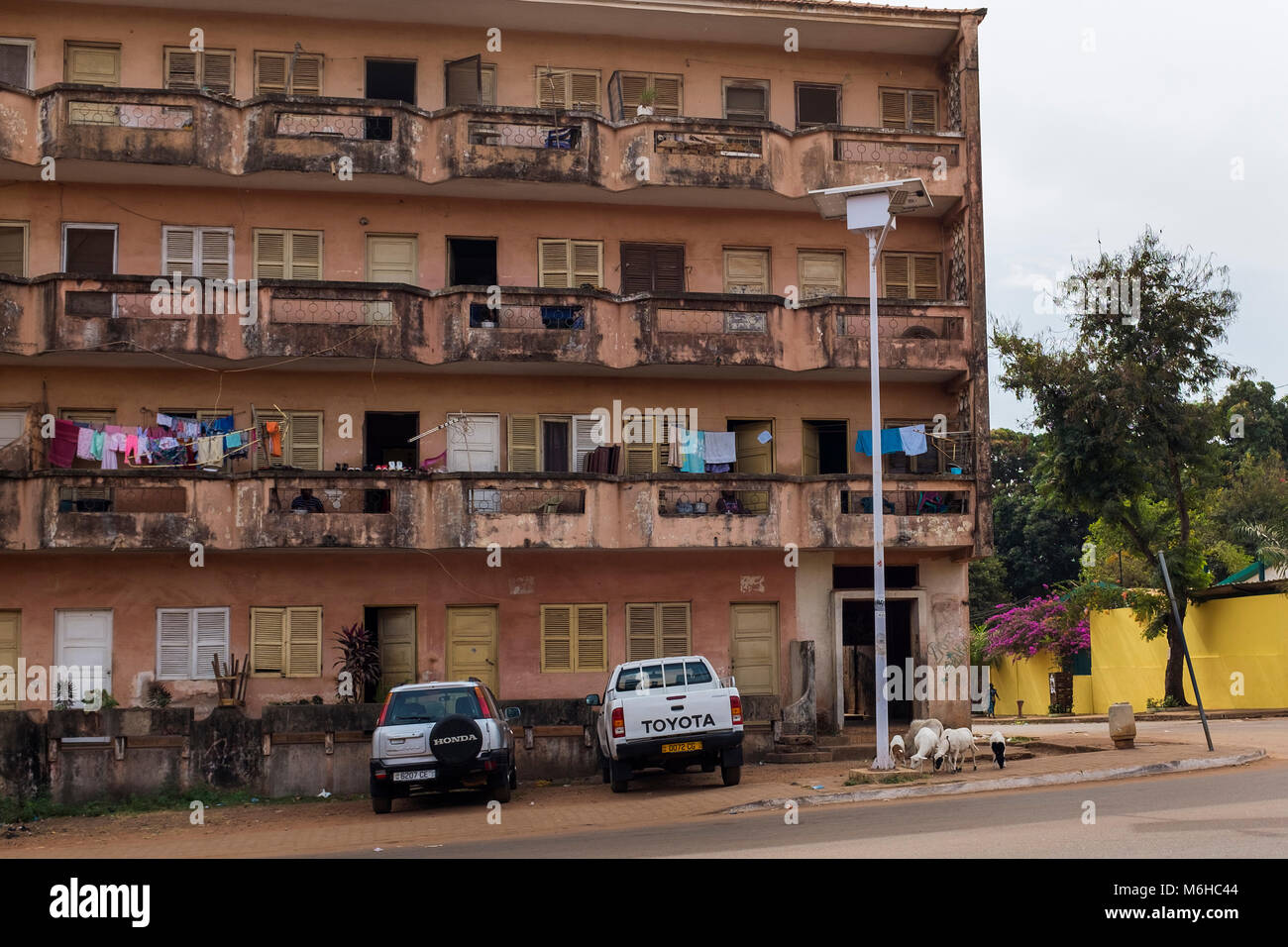 Bissau, Republic of Guinea-Bissau - January 28, 2018: An old and crumbling apartment building with goats at its entrance in the city of Bissau, Republ Stock Photo