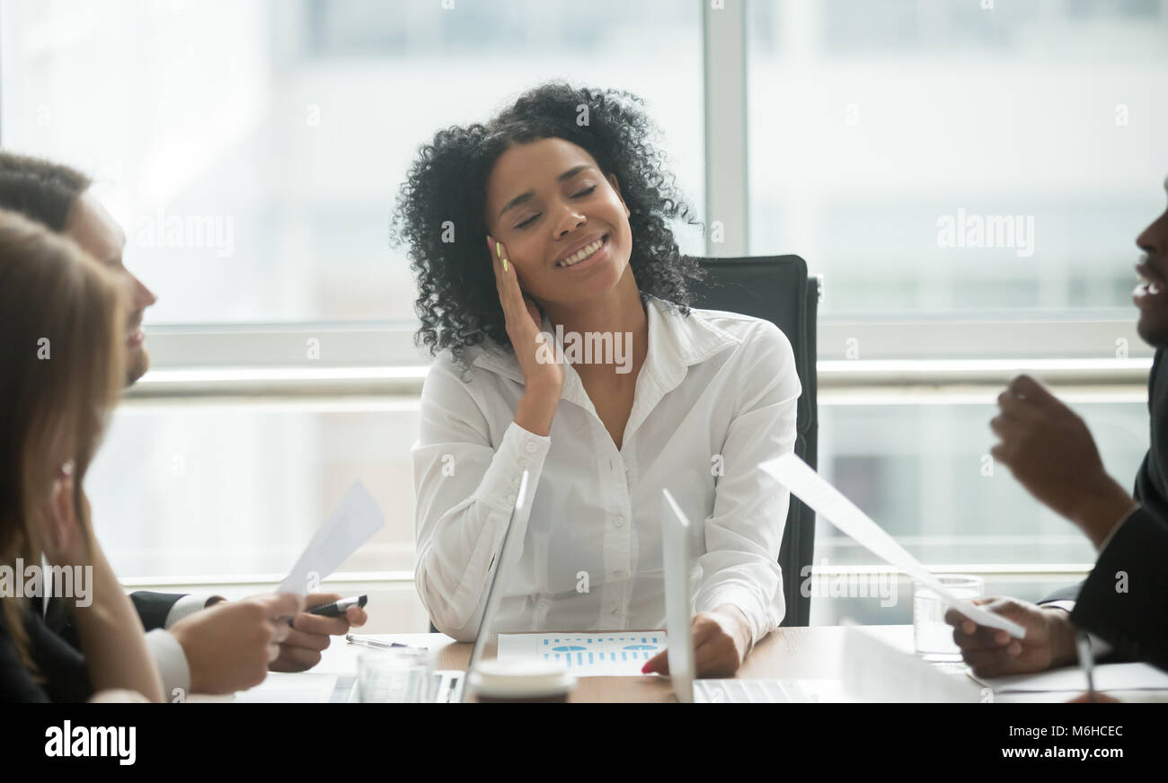 Absent-minded distracted black businesswoman dreaming smiling at Stock Photo