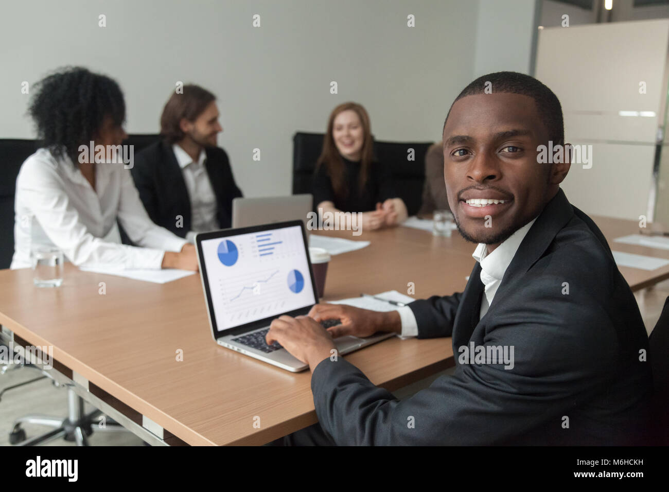 Smiling african-american businessman using laptop looking at cam Stock ...