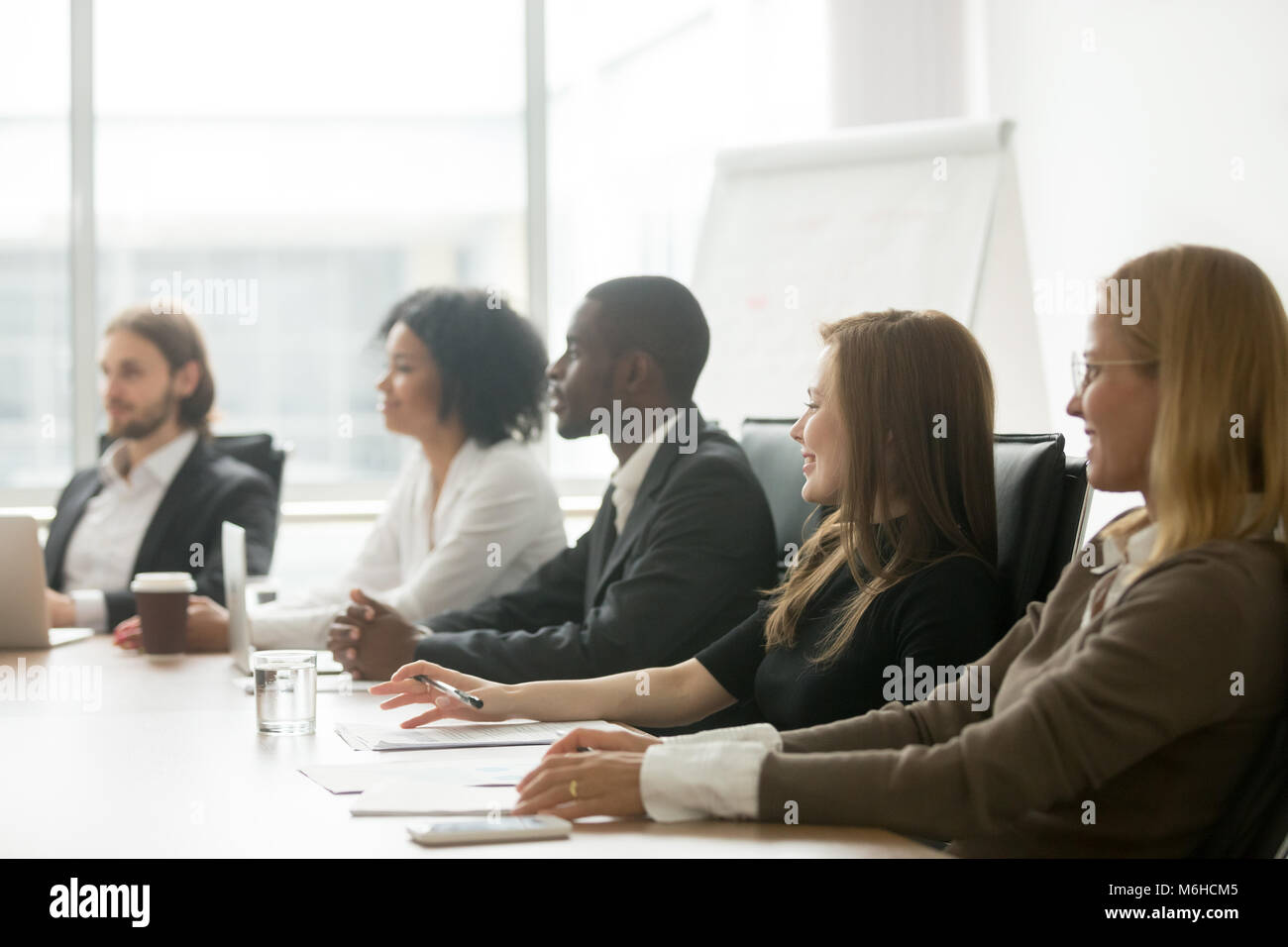 Diverse smiling businesspeople sitting at conference table at gr Stock Photo