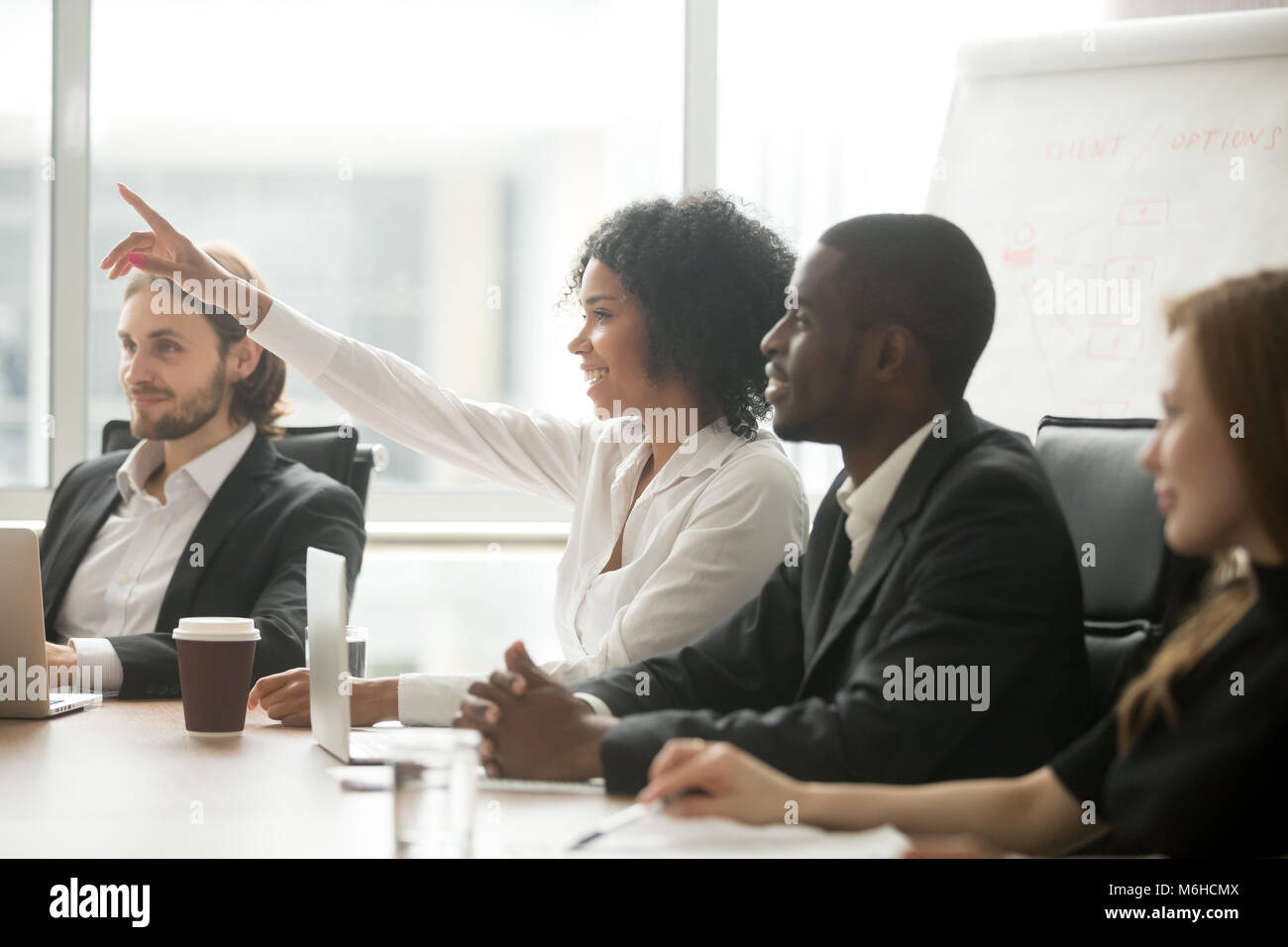 African woman raising hand to ask question at team training Stock Photo