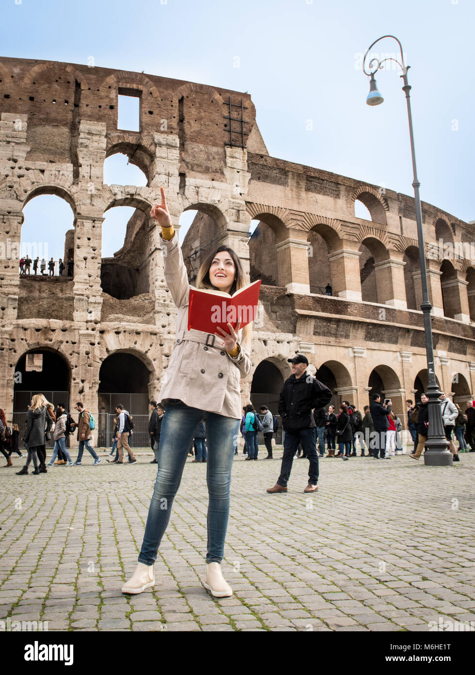 Young pretty tourist woman with travel book pointing out, colosseum monument in Rome Italy Stock Photo
