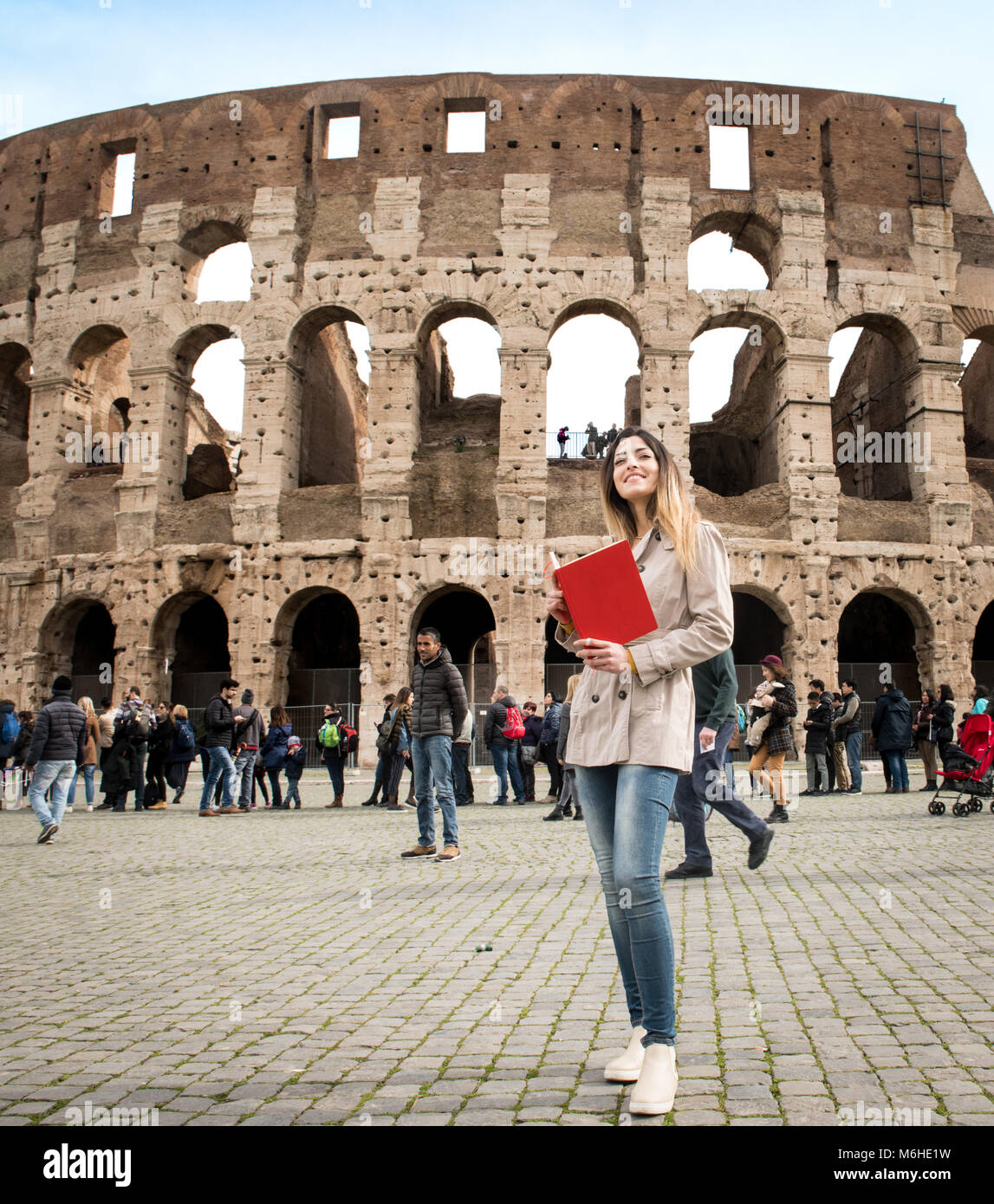 Young pretty tourist woman smiling with travel book, colosseum monument in Rome Italy Stock Photo