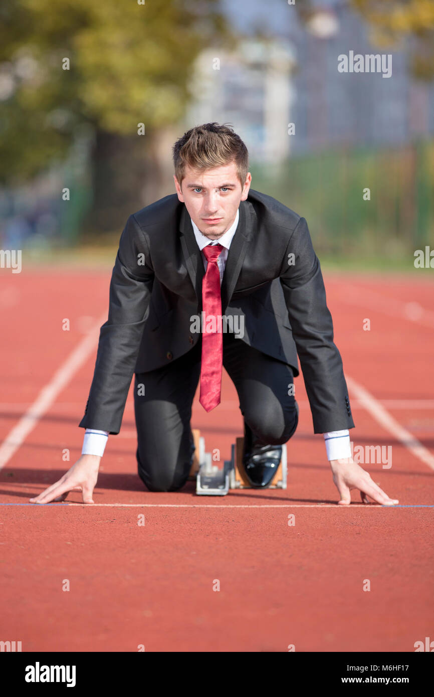 Business man in suit starting and preparing to run on the competition running performance track