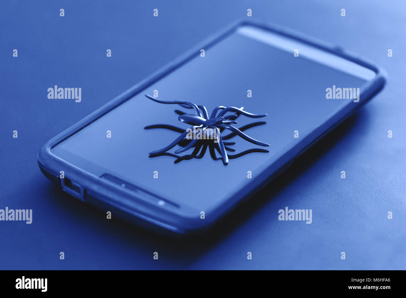 Plastic spider toy in action of running on surface of cell display. Great spider toy posing on surface of smartphone. Telecommunications. Stock Photo