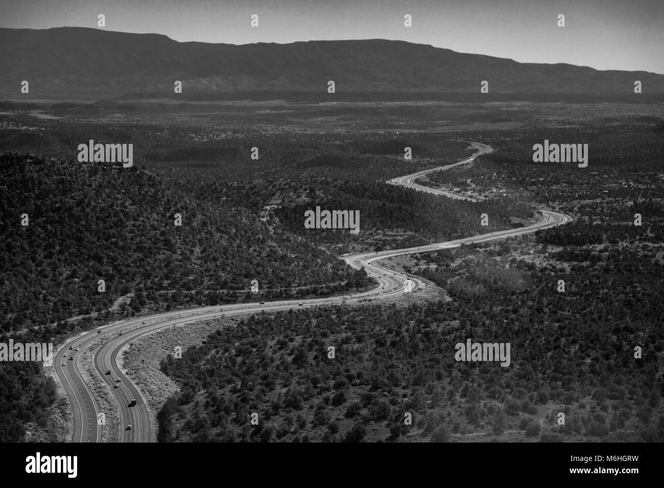 An expansive aerial landscape of an Arizona Highway winding through a grand forest, taken from a helicopter. Stock Photo