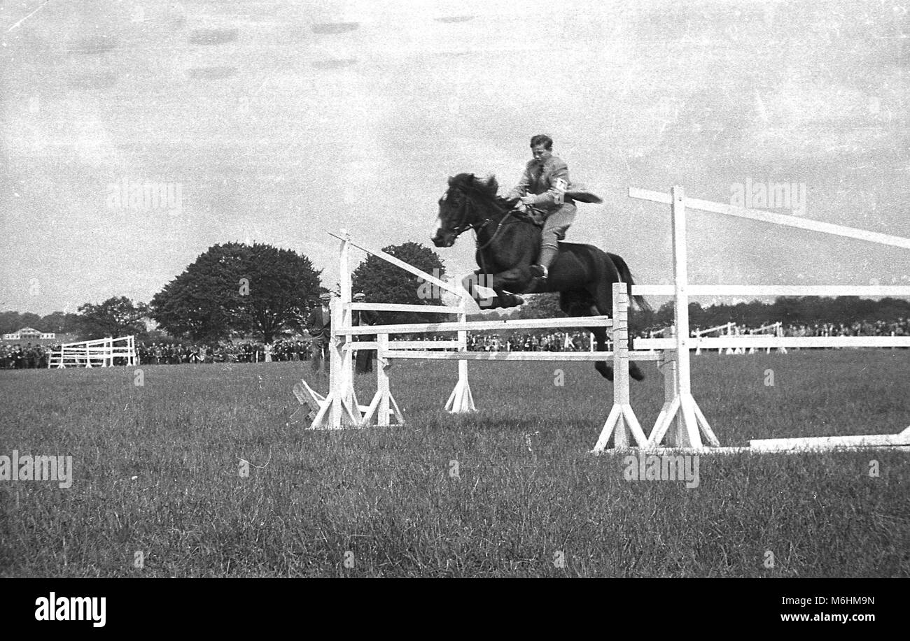 1940s, historical, a young man riding a horse - bareheaded - leaping over an obstacle or fence at an outdoor jumping event, England, UK. Stock Photo