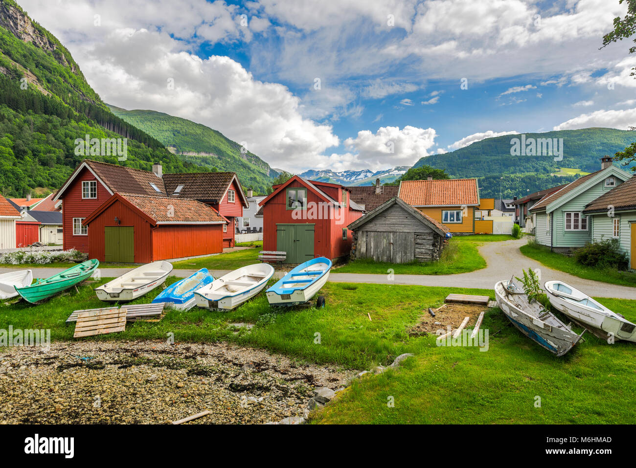 colourful huts and boats at the seashore in Vik i Sogn, Norway, snow-capped mountains in background, Sogn og Fjordane Stock Photo