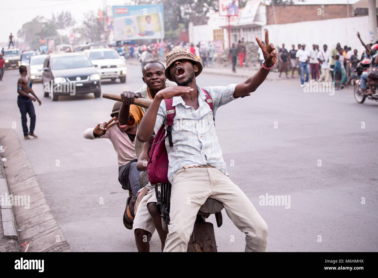 Revellers, riding on a wooden frame bicycle, the chukudu in Goma, motion cutting a throat after their Congo team won an international football match Stock Photo