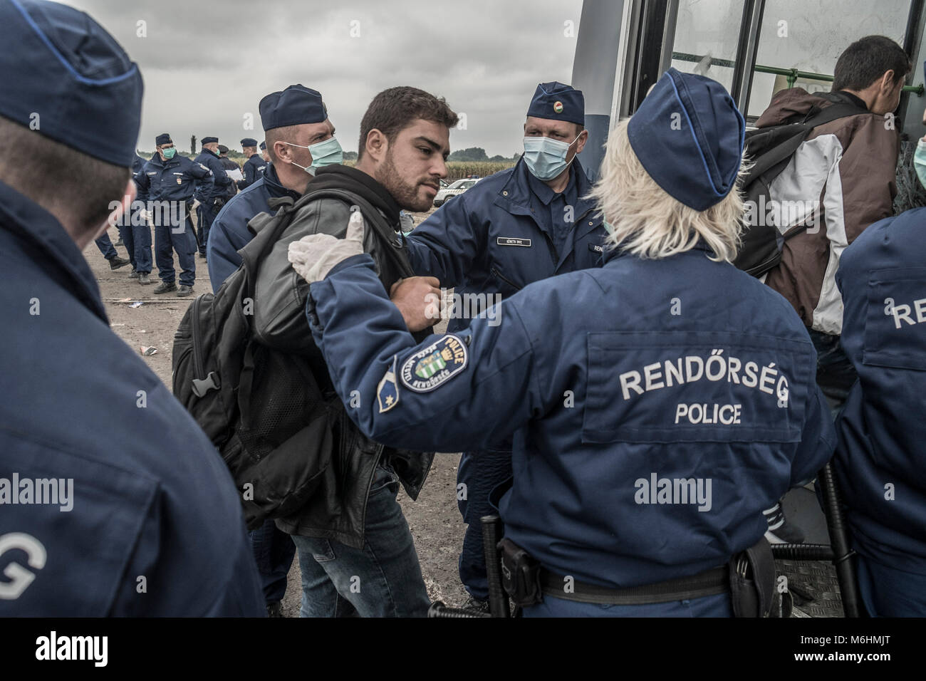 A male refugee voluntarily enters a police bus to go to a processing centre after walking along an old rail corridor into Hungary from Serbia. Stock Photo