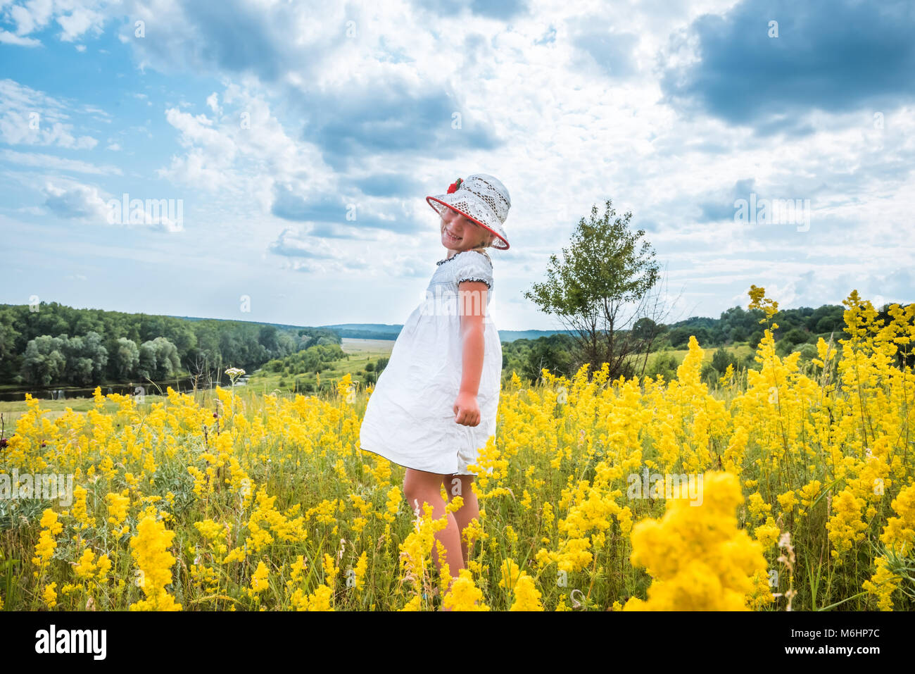 Cute little laughing girl walking in field of summer yellow flowers ...