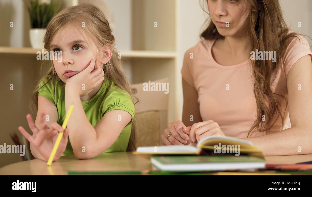 Little daughter ignoring mother making her to do homework, homeschooling Stock Photo