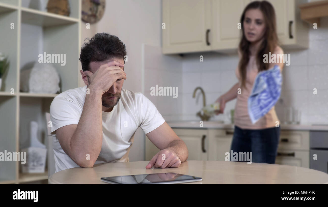 Possessive wife fighting with husband at home, accusing him of cheating, divorce Stock Photo