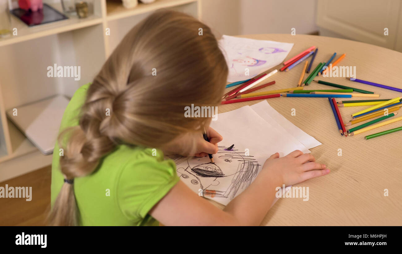 Little girl drawing stranger from her nightmare with black pencil, child fears Stock Photo