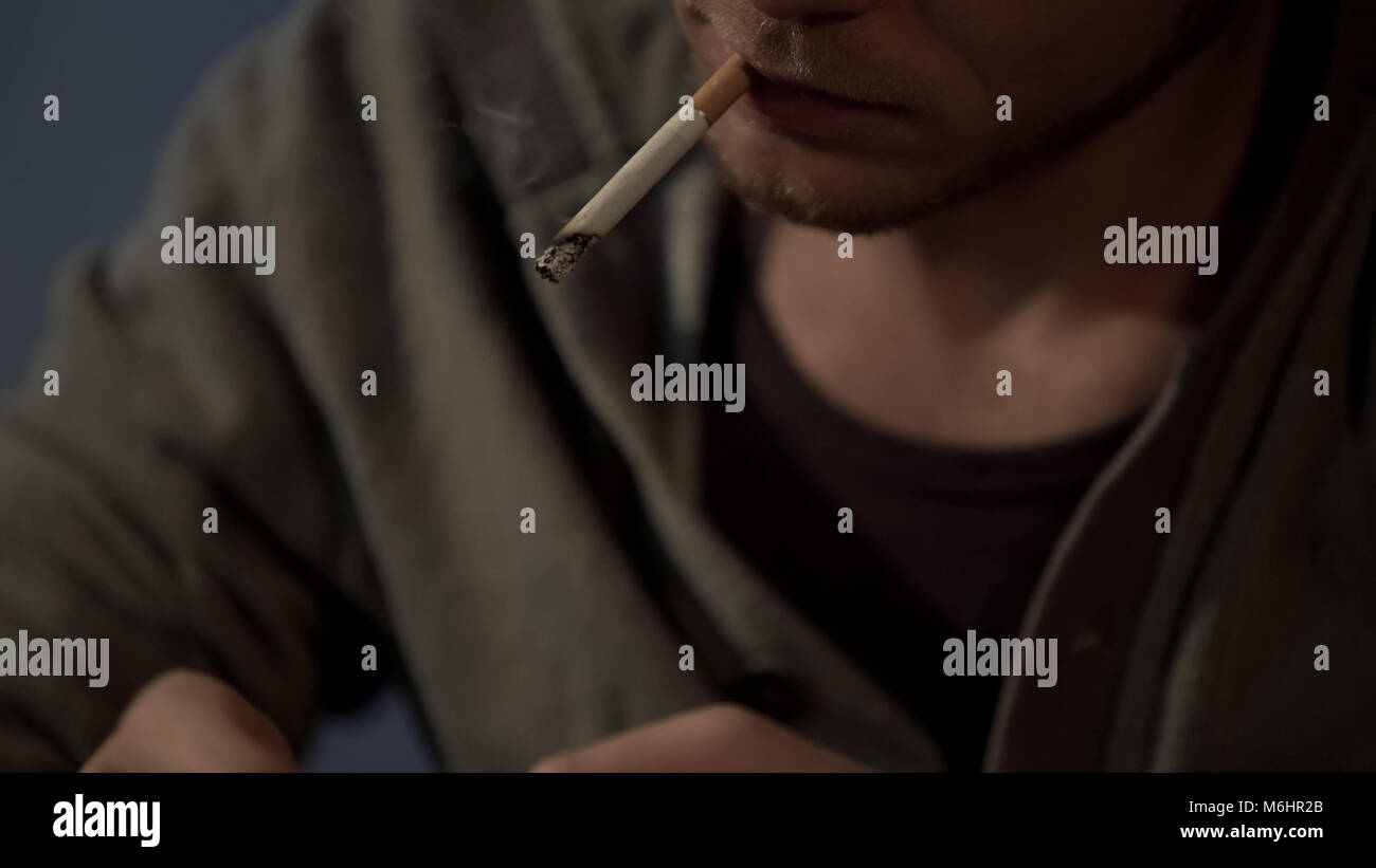 good looking depressed guy smoking a cigarette Young depressed man smoking in hi-res stock photography and images