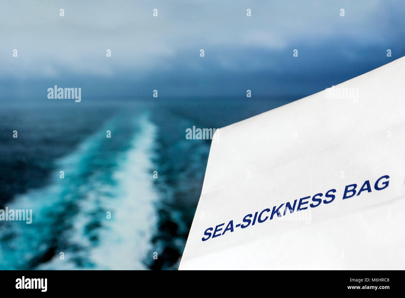 Sea sickness bag against a stormy ocean background with wake from a ship and a shallow depth of field Stock Photo