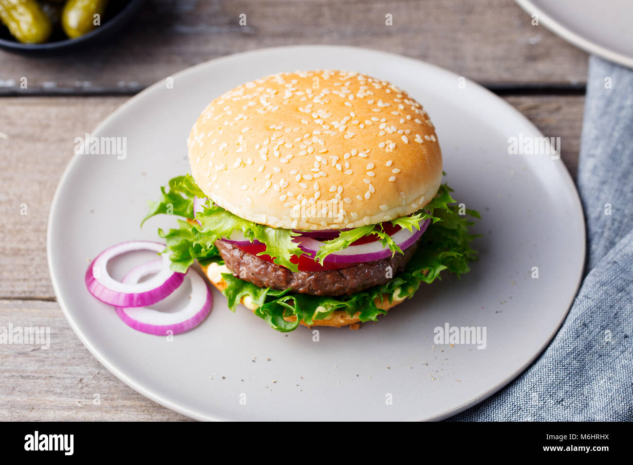 Burger on a plate with pickles. Wooden background Stock Photo