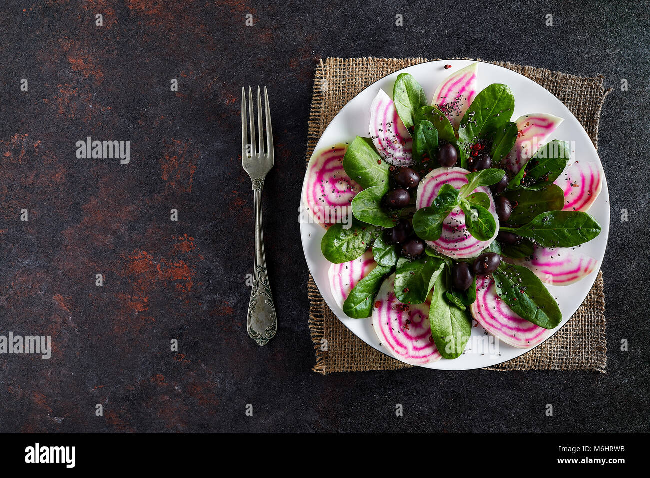 Plate with beet salad, from root to leaves, with some corn salad and black olives, overhead shot. Stock Photo