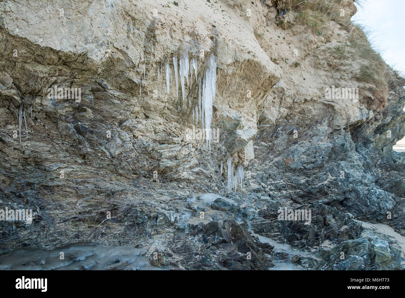 UK weather Icicles formed by water from the water table seeping through sand dunes at Crantock Beach in Newquay Cornwall. Stock Photo