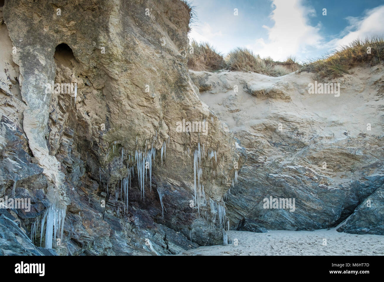 UK weather Icicles formed by water from the water table seeping through sand dunes at Crantock Beach in Newquay Cornwall. Stock Photo