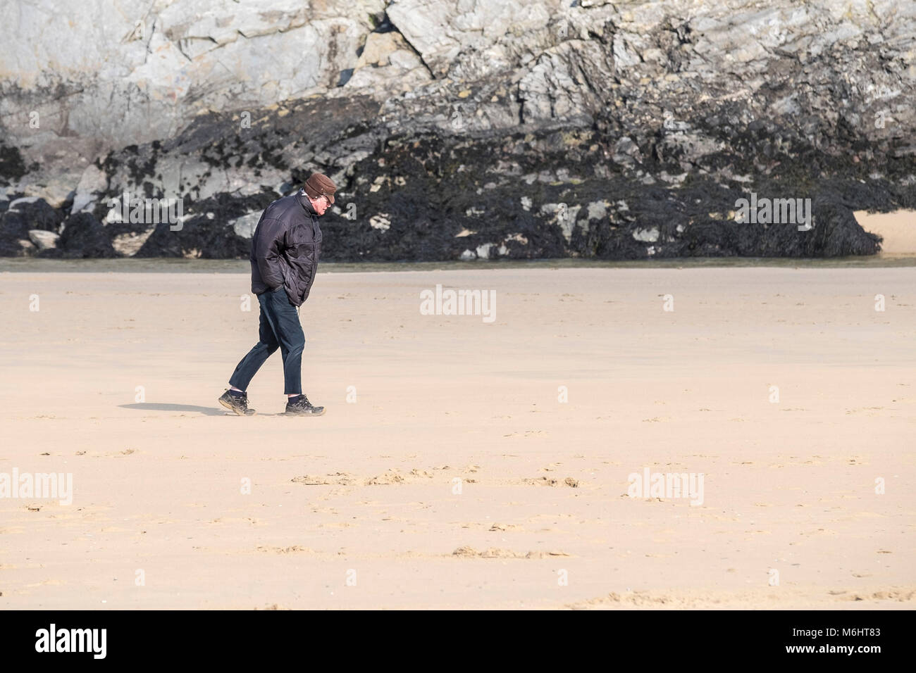 A man walking into the wind on Crantock Beach in Newquay Cornwall. Stock Photo