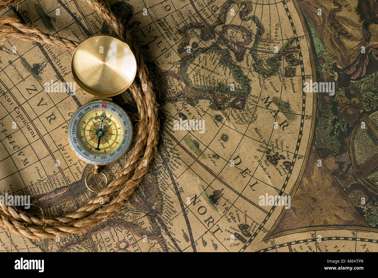 Old compass on vintage map with rope closeup. Retro stale Stock Photo