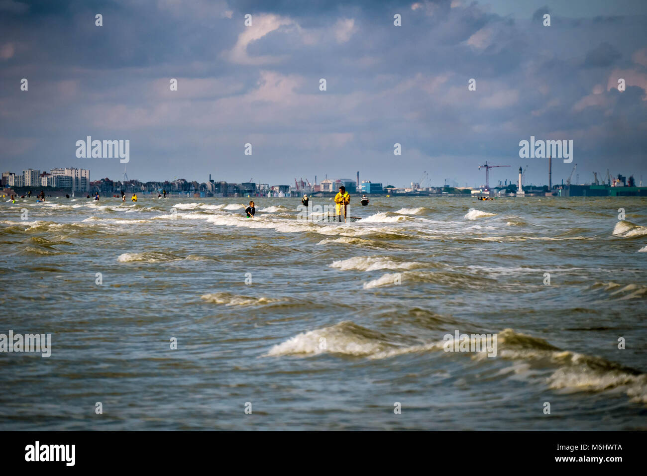 Father and son fishing in shallow waters in front of a industrial beachfront Stock Photo