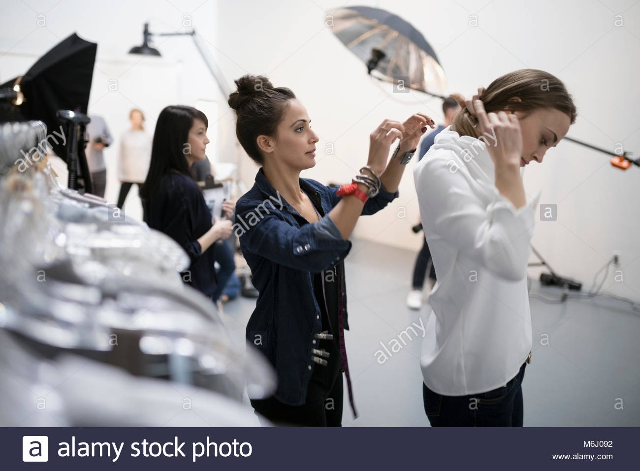 Female wardrobe stylist helping model trying on blouse at photo shoot