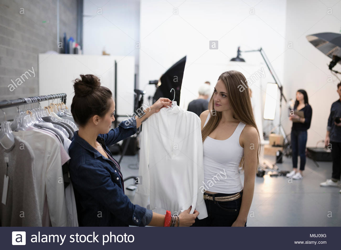 Female wardrobe stylist choosing blouse for model at photo shoot in