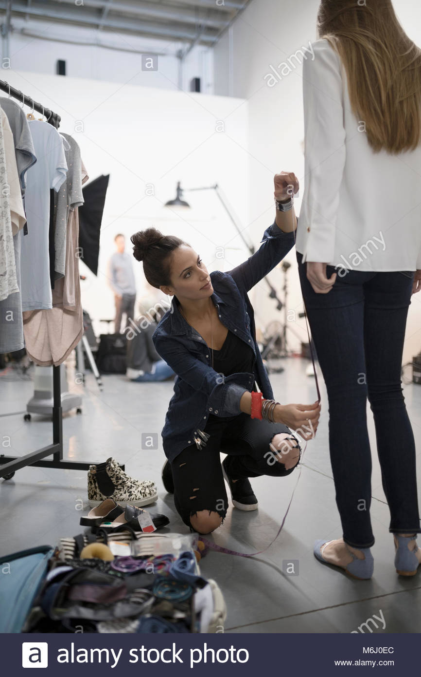 Female Wardrobe Stylist Measuring Model For Photo Shoot In Studio