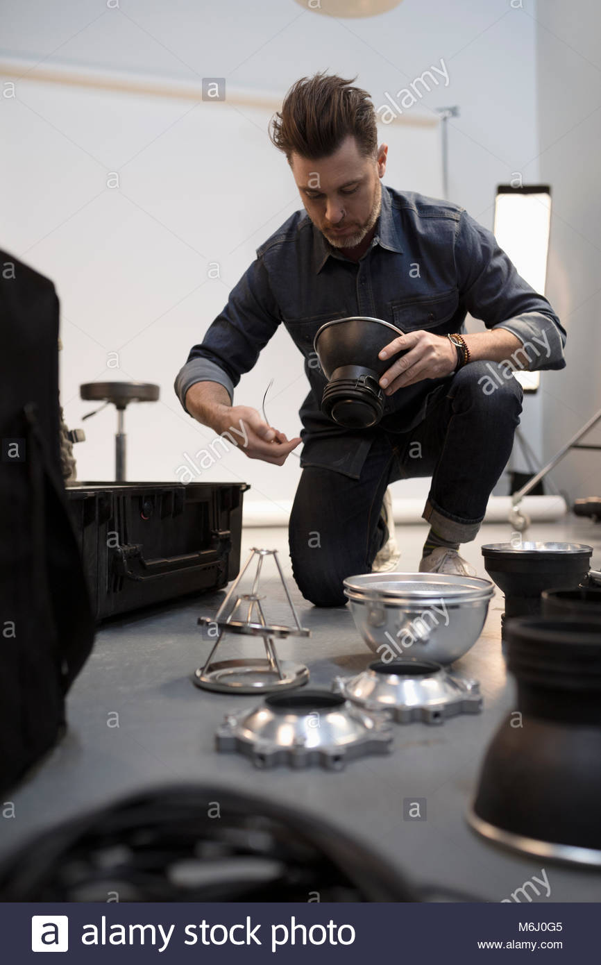 Male photographer preparing lighting equipment for photo shoot in studio Stock Photo