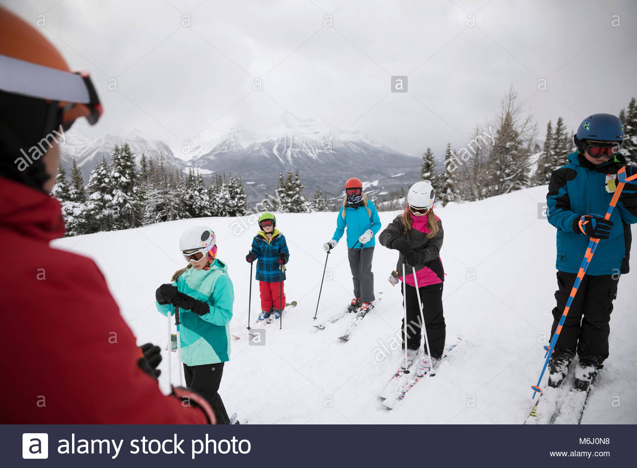 Kids receiving ski lesson from instructor on snowy mountain Stock Photo