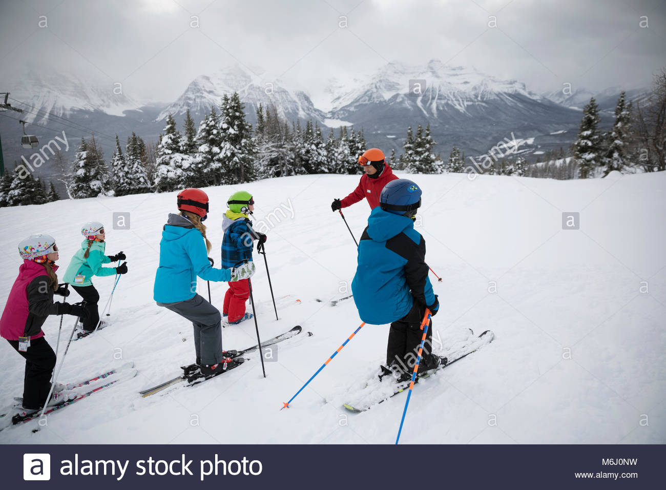 Kids receiving ski lesson from instructor on snowy mountain Stock Photo
