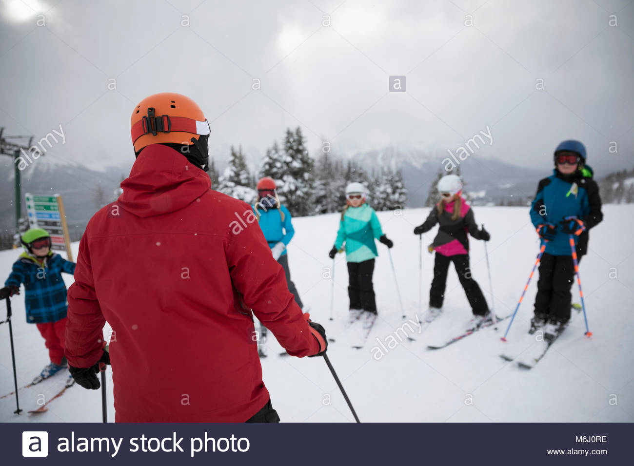 Kids receiving ski lesson from instructor on snowy mountain Stock Photo