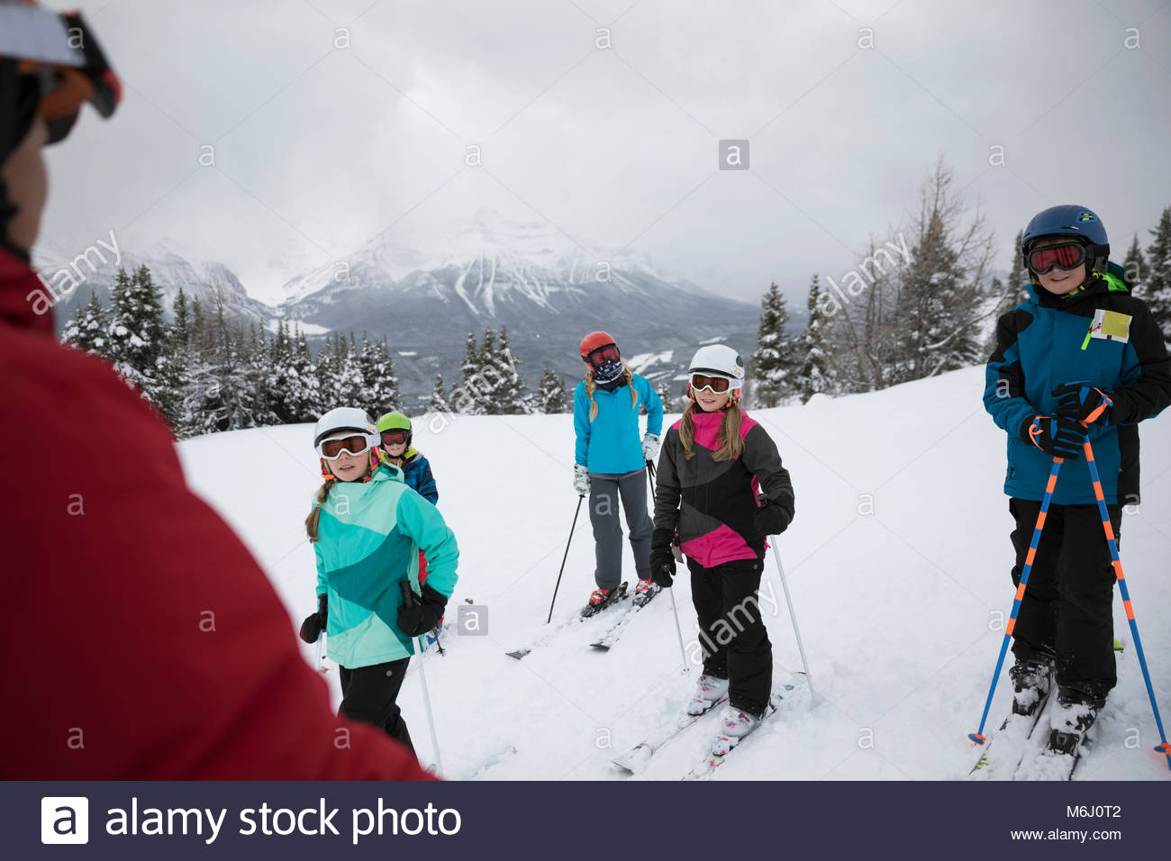 Kids receiving ski lesson from instructor on snowy mountain Stock Photo