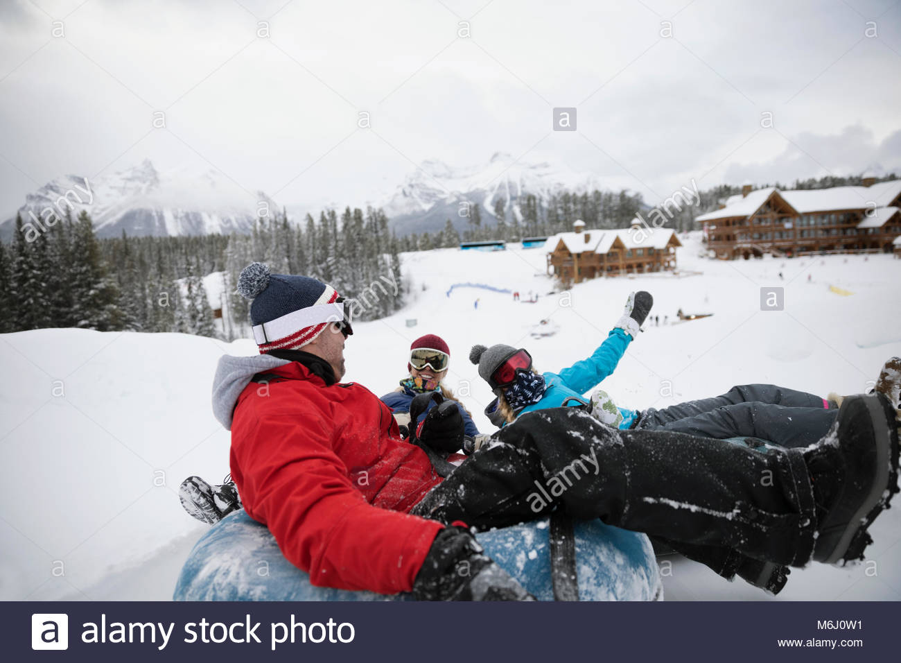 Playful family inner tubing in snow at ski resort tube park Stock Photo