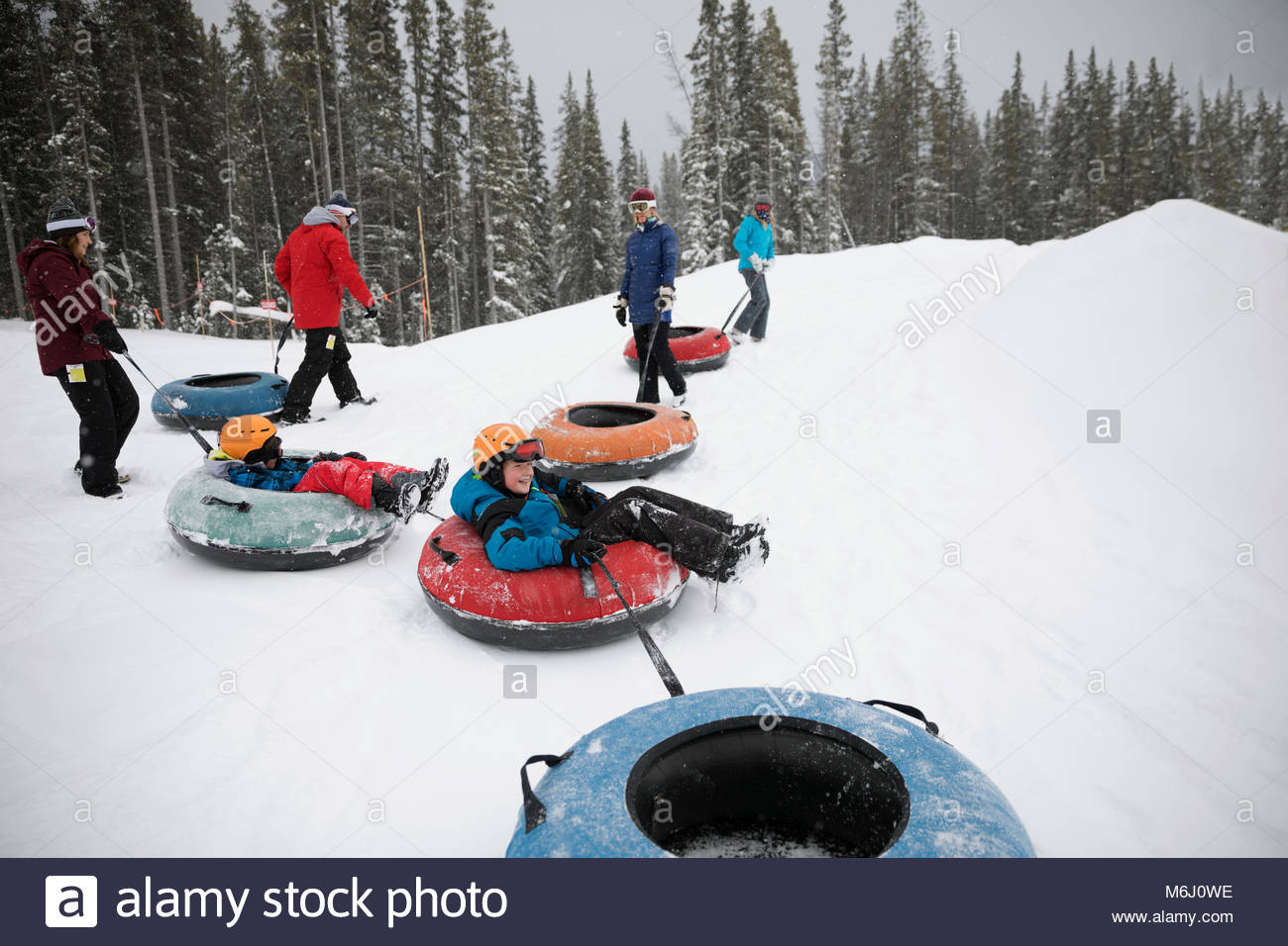 Family inner tubing in snow at tube park Stock Photo Alamy