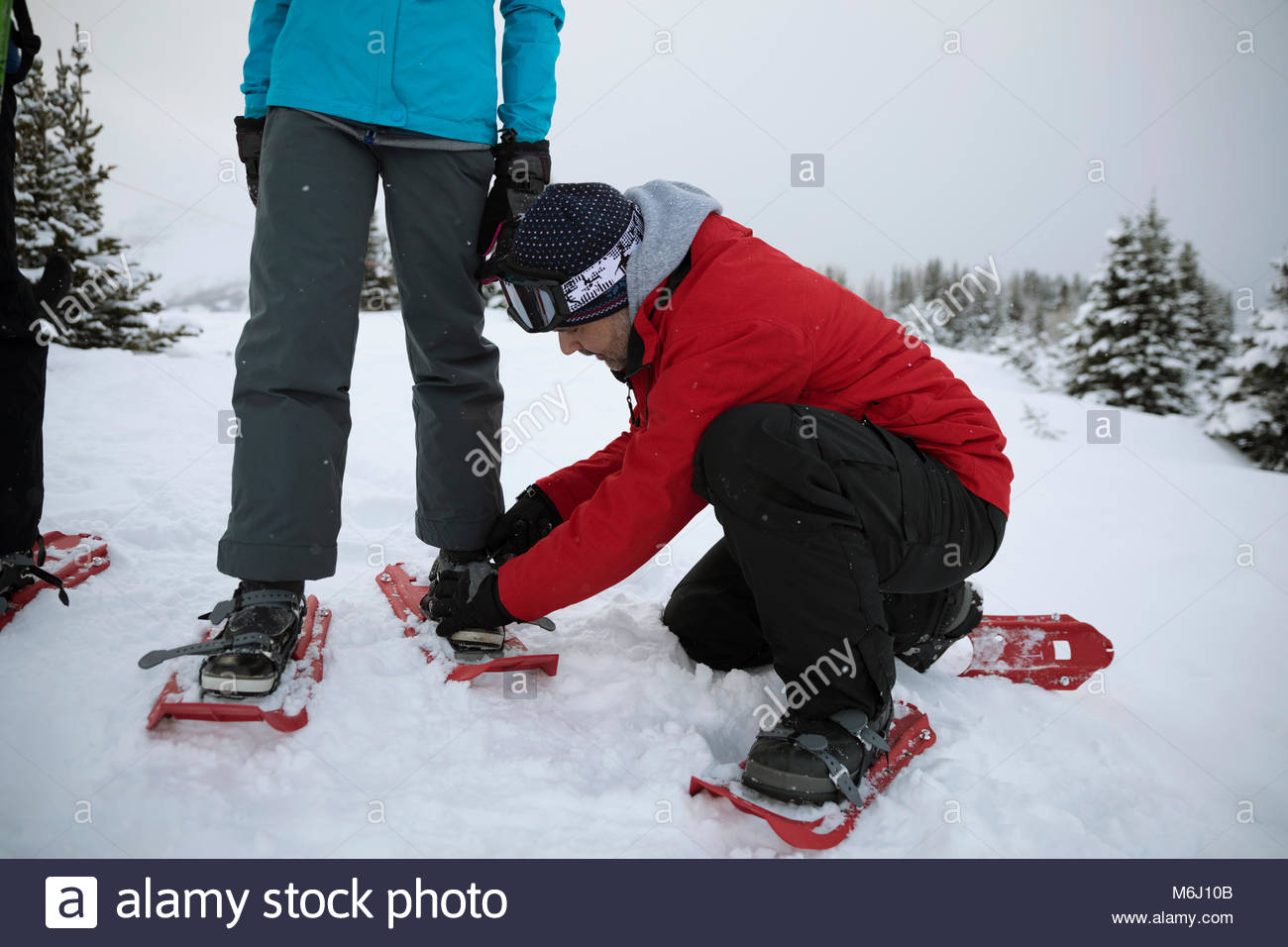 Father helping daughter put on snowshoes in snow Stock Photo Alamy