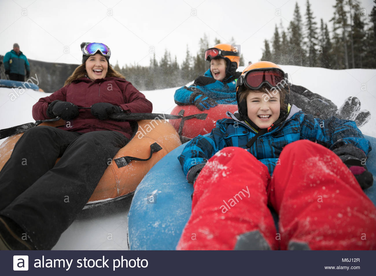 Happy mother and sons inner tubing in snow at tube park Stock Photo Alamy