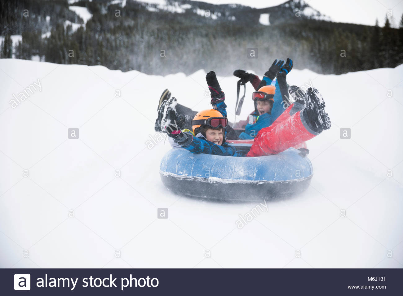 Playful brothers inner tubing in snow at tube park Stock Photo Alamy